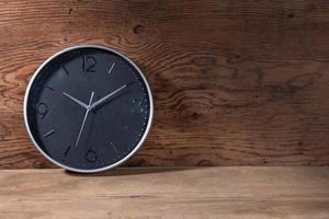 relógio preto sobre fundo de madeira marrom foto