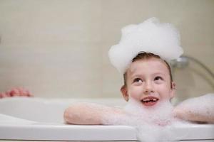 menina no banho brincando com espuma de sabão foto