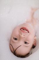 menina no banho brincando com espuma de sabão foto