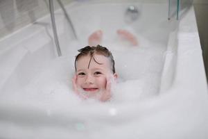 menina no banho brincando com espuma de sabão foto