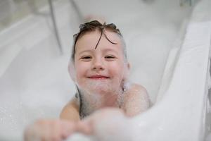 menina no banho brincando com espuma de sabão foto