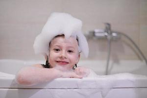 menina no banho brincando com espuma de sabão foto