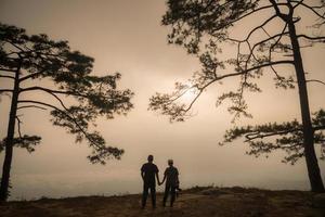 a silhueta de pinheiro e casal no parque nacional phu kradueng da província de loei da tailândia. foto