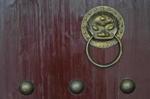 maçaneta da porta do ornamento chinês do leão dourado vintage no portão vermelho foto