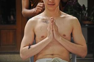 cortar o cabelo durante a meditação em uma ordenação para ser monge tailandês foto