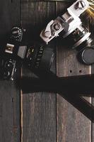 câmera de filme retrô e filme negativo em uma mesa de madeira preta foto