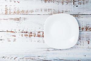 um prato branco redondo vazio em uma mesa de madeira azul. foto