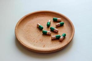 cápsulas solúveis intestinais com vitaminas em uma placa de madeira.