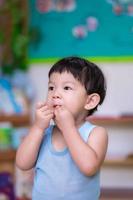 conceito de saúde e mãos limpas. retrato de menino usando as mãos alimentando macarrão de comida na boca. criança com fome. no dia nublado. criança fofa de 1 a 2 anos. foto