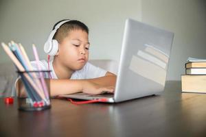 jovem estudante a distância virtual aula on-line a distância na aula virtual de videochamada, tecnologia estudando em casa usando o computador portátil. pai ou tutor ensinando criança menino com educação remota. foto