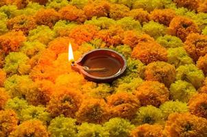 flor de calêndula decorativa rangoli para o festival de diwali com lâmpada de argila diya acesa com chama. foto