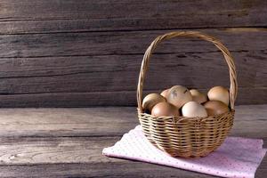 ovos em uma cesta de vime na mesa de madeira foto