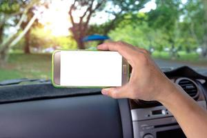 carro e mão humana segurando o telefone móvel em branco foto