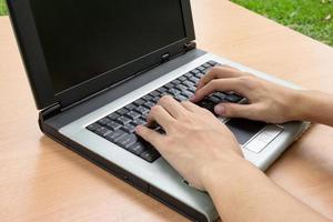 homem usando laptop na mesa de madeira foto