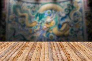 mesa de madeira com parede de estátua de dragão fundo desfocado foto