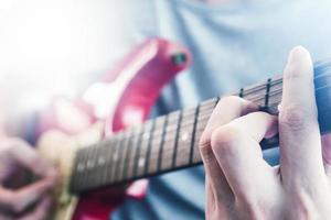 close-up de mãos masculinas tocando guitarra elétrica, reflexo da luz do sol, foco seletivo foto