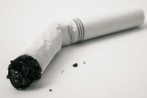 ponta de cigarro com cinzas em um fundo branco. foto