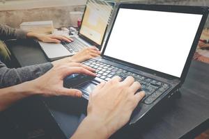 parceiros de negócios trabalhando juntos na mesma mesa, eles estão usando um laptop com tela em branco, iniciar o conceito de negócios foto