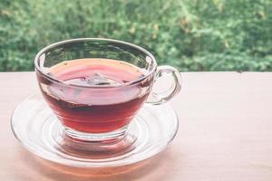 uma xícara de chá na mesa de madeira, saquinho de chá em vidro, fundo da natureza. foto