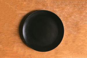 vista superior do prato preto vazio na mesa de madeira foto
