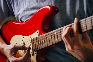 close-up de mãos masculinas tocando guitarra elétrica. foco seletivo foto