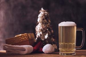 caneca de cerveja com enfeites de natal na mesa de madeira. foto