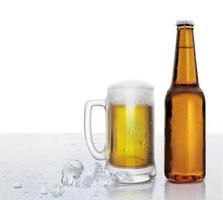 copo e garrafa de cerveja com gotas de água e cubos de gelo no fundo branco foto