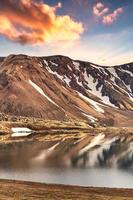 cordilheira vulcânica com céu coberto de neve e pôr do sol nas terras altas islandesas em landmannalaugar na islândia foto