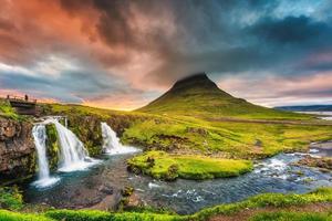 paisagem do pôr do sol sobre a montanha kirkjufell com cachoeira kirkjufellsfoss e nuvem colorida pileus no verão na islândia foto