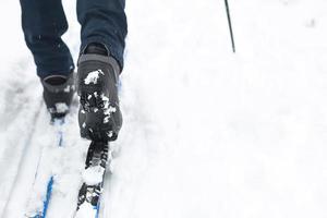 pés de um esquiador em botas de esqui em esquis cross-country. andando na neve, esportes de inverno, estilo de vida saudável. close-up, copyspace foto