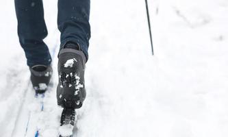 pés de um esquiador em botas de esqui em esquis cross-country. andando na neve, esportes de inverno, estilo de vida saudável. close-up, copyspace foto