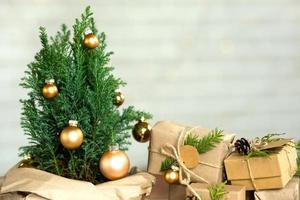 cipreste interior em pote é decorado com bolas como árvore de natal com luzes de fadas. caixas de presente com decoração natural para ano novo e natal. ecologicamente correto, zero desperdício, planta em casa, casa verde. espaço de cópia foto