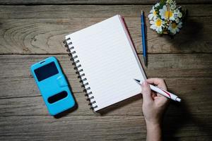 mão humana segurando caneta com caderno aberto foto