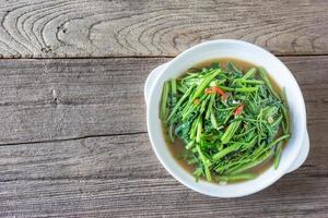 mexa espinafre de água frita ou pak boong fai daeng no prato branco foto
