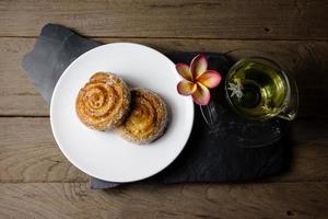 rolos de canela com chá de crisântemo em fundo de madeira foto