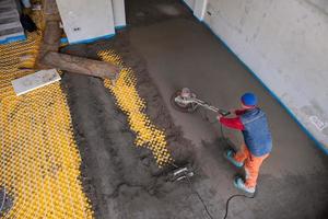 trabalhador realizando e polindo piso de betonilha de areia e cimento foto