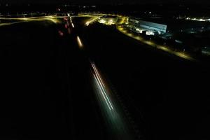 vista aérea noturna das autoestradas britânicas com estradas iluminadas e tráfego. imagens de rodovias tiradas com a câmera do drone sobre milton keynes e rodovias da inglaterra à noite escura foto