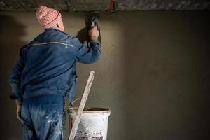 trabalhador rebocando a parede de concreto foto
