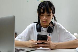 garota usando fones de ouvido estudando on-line com o laptop do computador e ouvindo música relaxante ou reproduzindo mídias sociais da internet em casa. foto