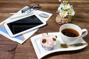 café com bolo no vapor e equipamento de escritório na área de trabalho foto