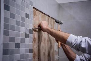 trabalhador remover demolir azulejos antigos em um banheiro foto