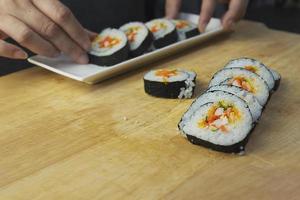 rolo de sushi maki japonês servindo no restaurante oriental, o chef está preparando o menu de culinária da tradição japonesa, vários conceitos de conjunto de alimentação saudável misto de luxo sortido diferente foto