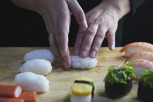 rolo de sushi maki japonês servindo no restaurante oriental, o chef está preparando o menu de culinária da tradição japonesa, vários conceitos de conjunto de alimentação saudável misto de luxo sortido diferente foto