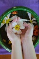 mão feminina e flor na água foto