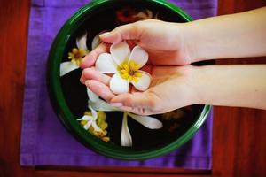 mão feminina e flor na água foto