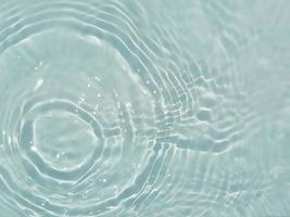 desfocar textura de superfície de água calma transparente de cor azul transparente turva com salpicos e bolha. fundo de natureza abstrata na moda. onda de água na luz solar com espaço de cópia. textura de aquarela azul foto