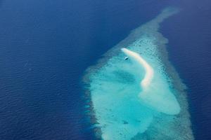 imagens aéreas da lagoa do oceano tropical azul turquesa, praia de areia branca, águas rasas de recifes de corais de banco de areia com um barco. perfeição da natureza no mar das maldivas. experiência de vida de luxo, paisagem pacífica foto