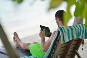 homem relaxando e use tablet na praia foto