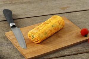 tamagoyaki, colocado em uma tábua de madeira e omelete de rolinho de ovo estilo japonês foto