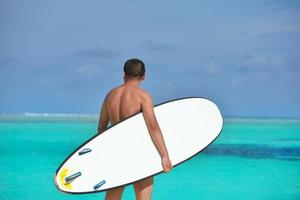 homem com prancha de surf na praia foto